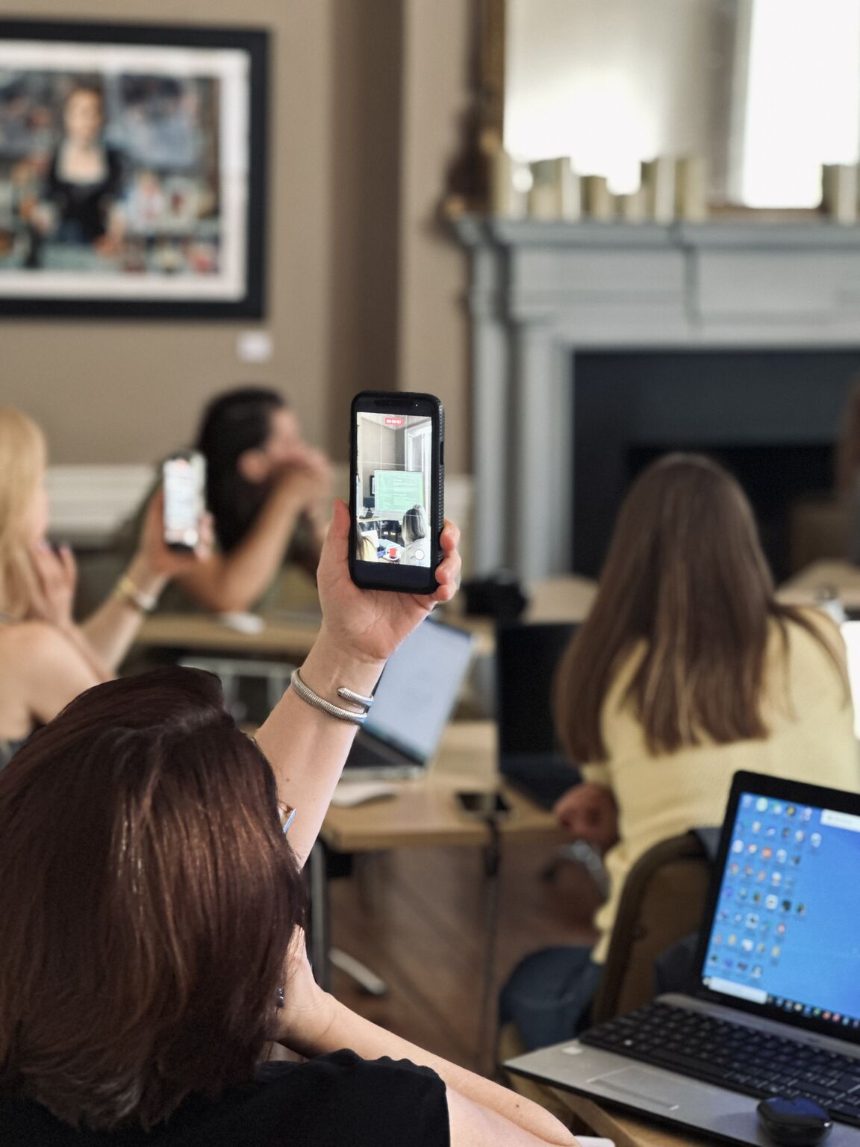 Members holding their phones up to photograph the screen during a Zorya AI session