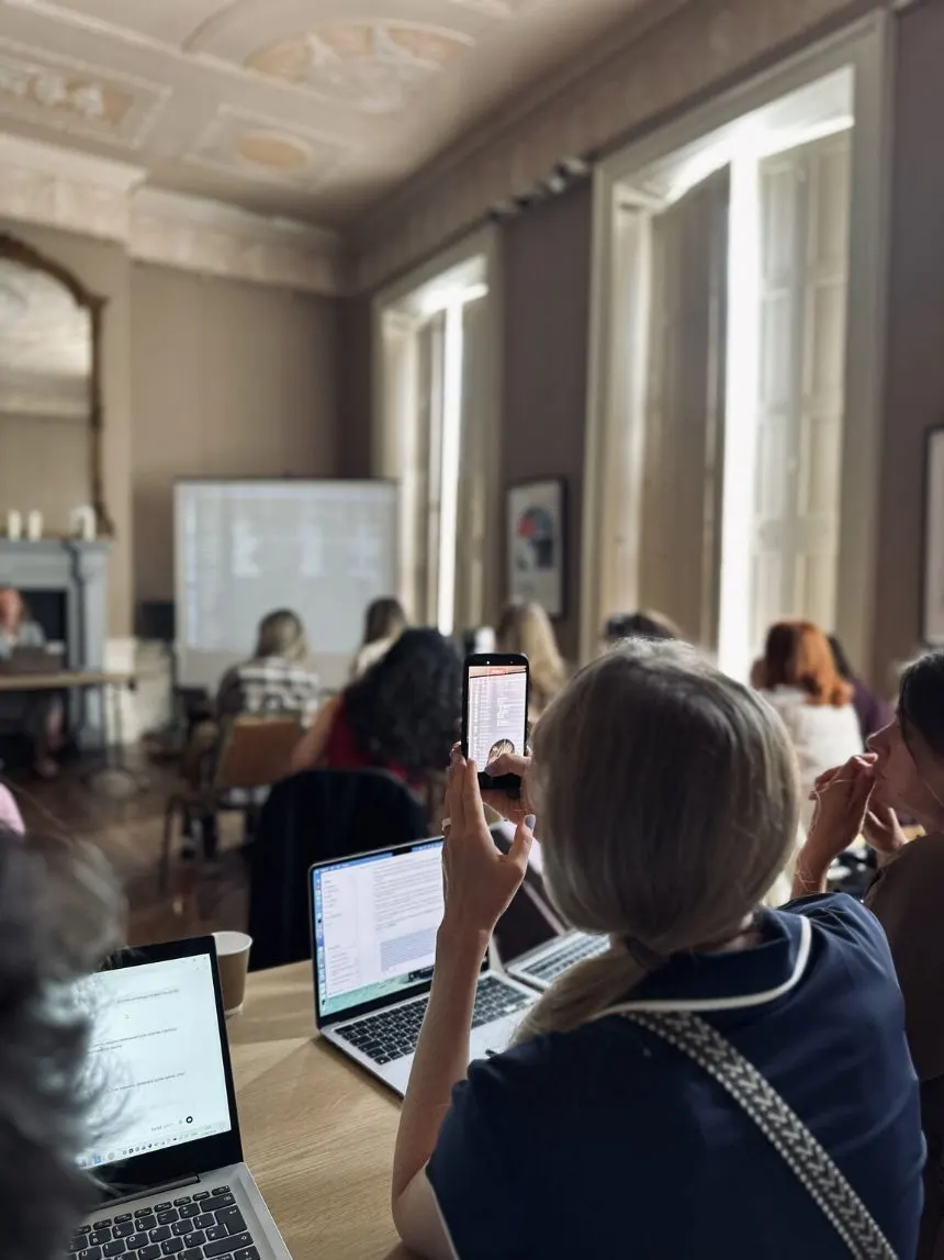 A high-ceilinged room of women at laptops facing the projected screen during a Zorya AI meetup